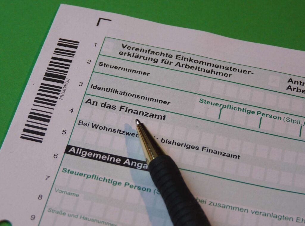 A person filling out a German Tax Return (Steuererklärung) form with a pen for Income Tax (Einkommensteuer).